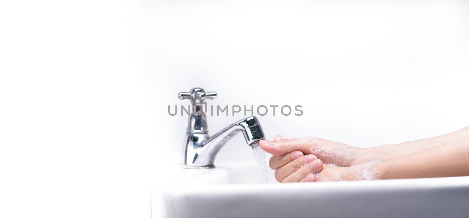 Woman washing hand with soap foam and tap water in bathroom. Han by Fahroni