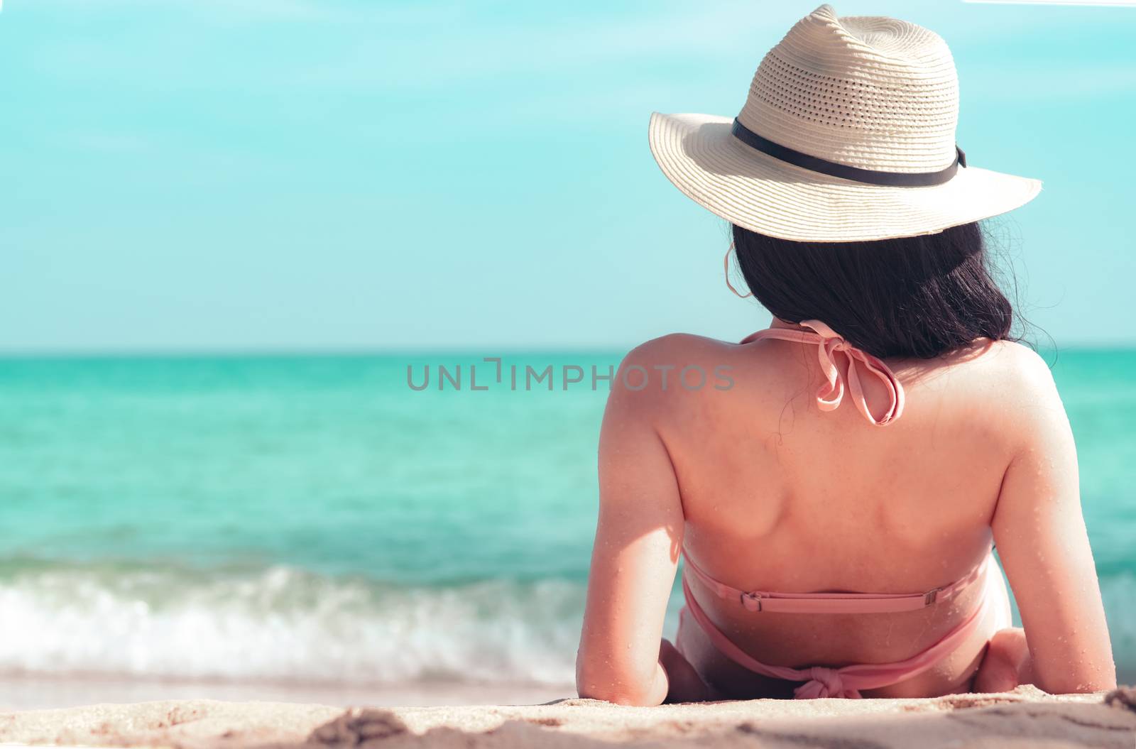 Back view of happy young Asian woman in pink swimsuit and straw  by Fahroni