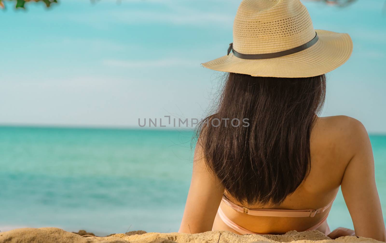 Back view of happy young Asian woman in pink swimsuit and straw  by Fahroni