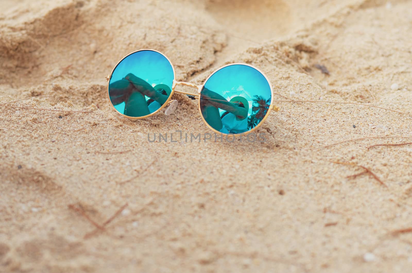 Sunglasses put on sand beach. Reflection of woman sit on sand beach in sunglasses. Women wear straw hat relax at tropical beach on summer vacation. Sunny day on holiday. Travel alone on summer.