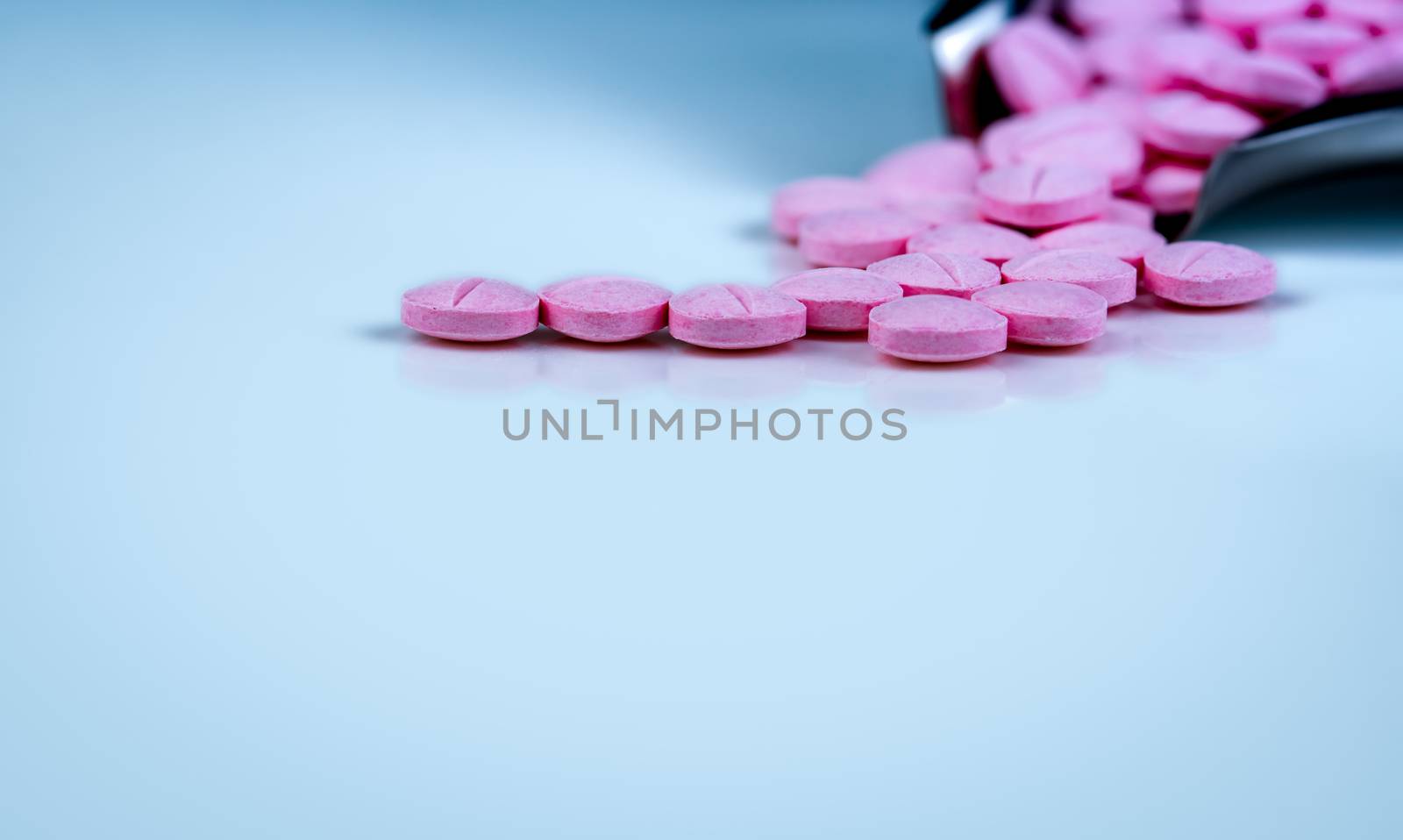 Pink tablets pills on blurred background of drug tray. Pharmaceutical industry. Pharmacy products. Vitamins and supplements. Medication use in hospital or drugstore. Global drug retail market. 