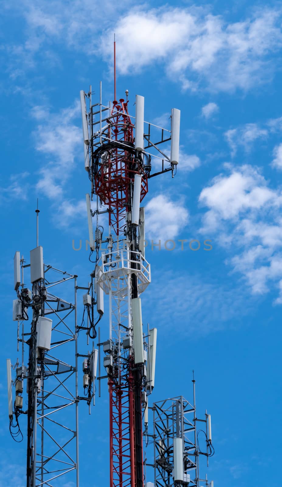 Telecommunication tower with blue sky and white clouds background. Antenna on blue sky. Radio and satellite pole. Communication technology. Telecommunication industry. Mobile or telecom 4g network.