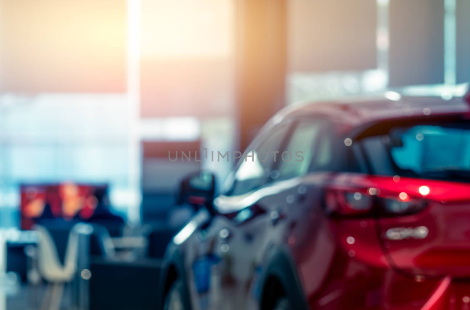 Blurred rear view of red car. Luxury car parked in modern showroom. Car dealership office. Automobile retail shop. Electric and hybrid car business concept. Automobile leasing. Automotive industry.