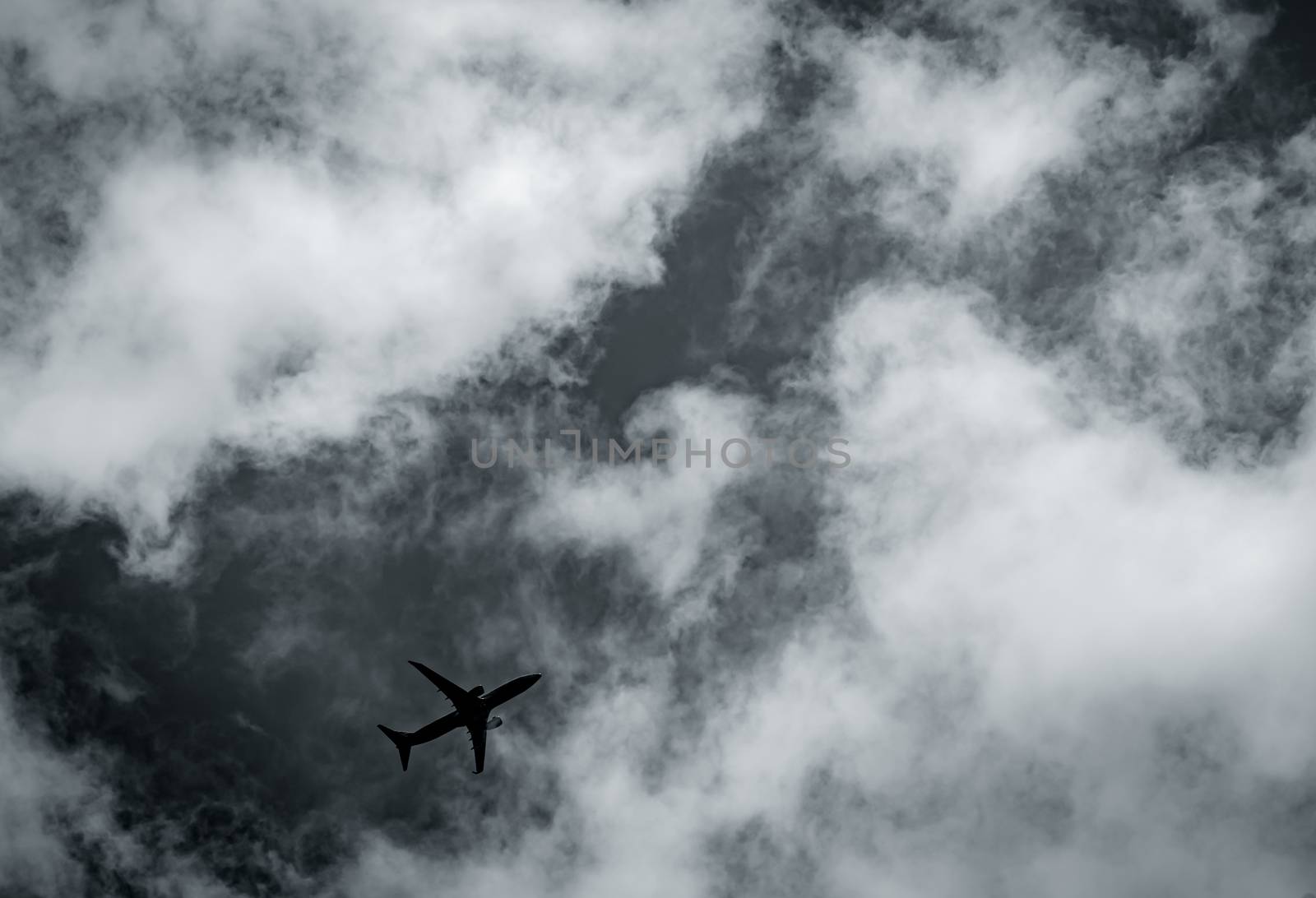 Airplane flying on dark sky and white clouds. Commercial airline with dream destinations concept. Aviation business crisis concept. Failed journey vacation flight. Air transportation. Sad travel.