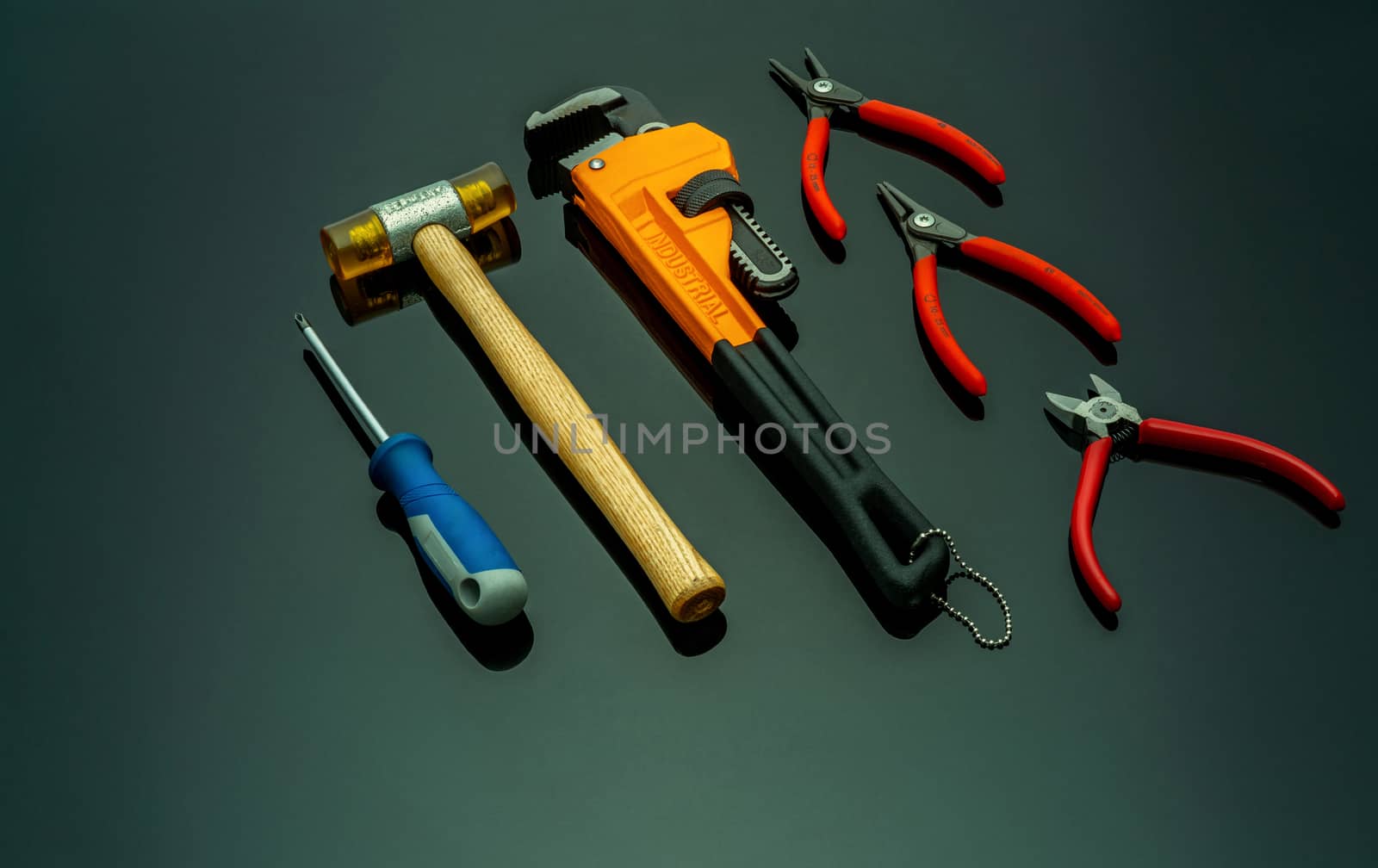 Set of mechanic tools isolated on black background. Screwdriver, red end cutter pliers, locking pliers, pincers, plastic hammer with wooden handle, and monkey pipe wrench. Tools for technician to fix.