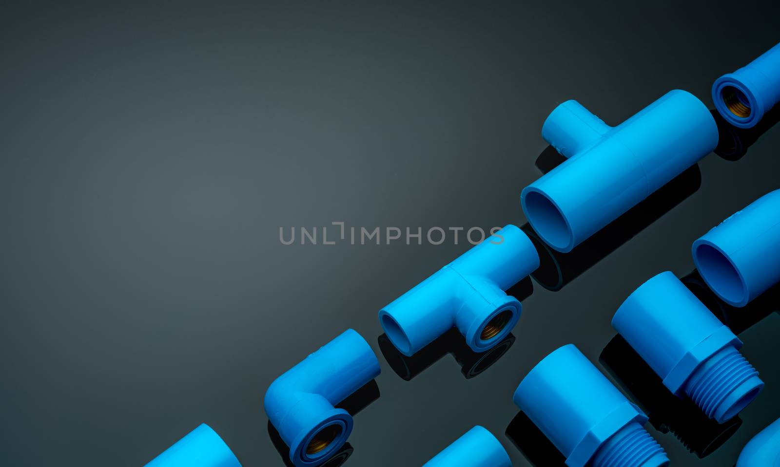 Set of blue PVC pipe fittings isolated on dark background. Blue plastic water pipe. PVC accessories for plumbing. Plumber equipment. Bend and three way connection plastic pipe for water drain sewage.