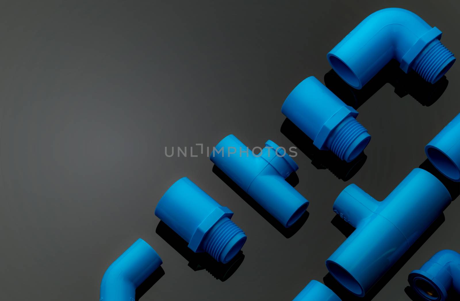 Set of blue PVC pipe fittings isolated on dark background. Blue plastic water pipe. PVC accessories for plumbing. Plumber equipment. Bend and three way connection plastic pipe for water drain sewage.