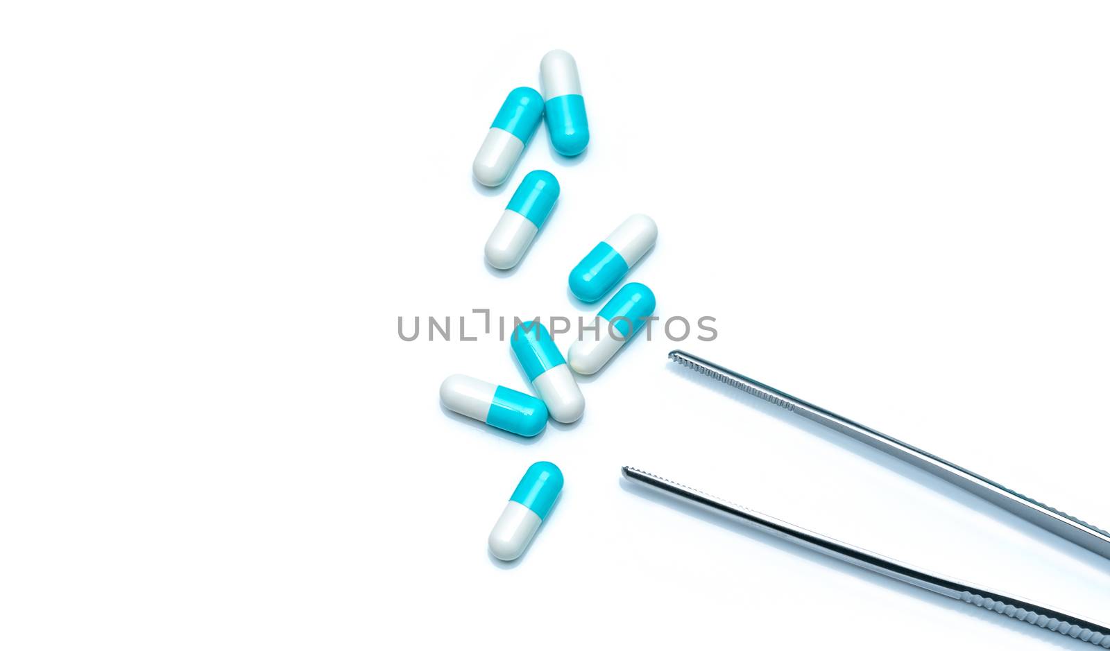 Eight blue-white capsules with stainless steel forcep isolated on white background. Colorful capsule pills. Pharmacy products. Pharmaceutics concept. Drugs sample selection in laboratory for research.