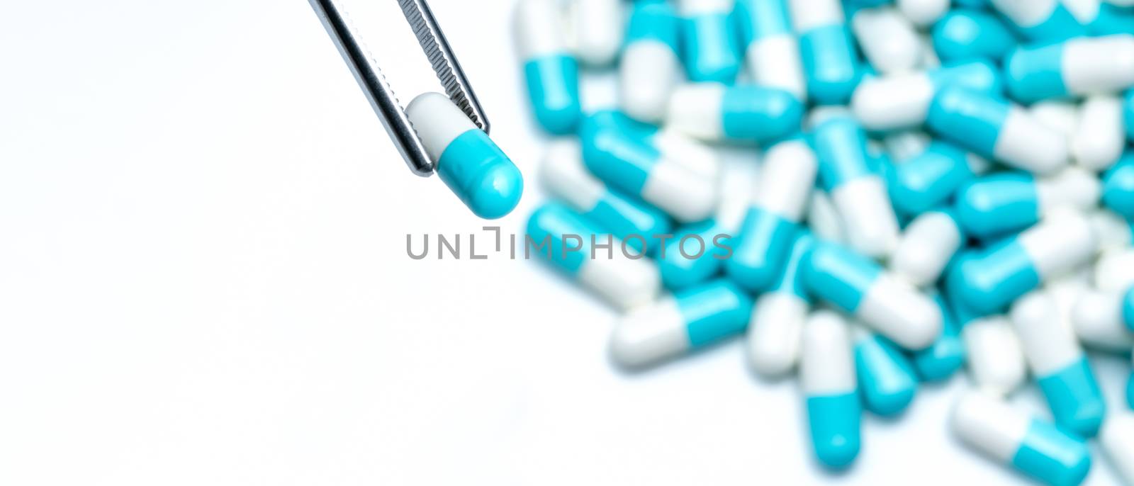 Forceps pick white-blue capsule from group of capsule pills. Dru by Fahroni