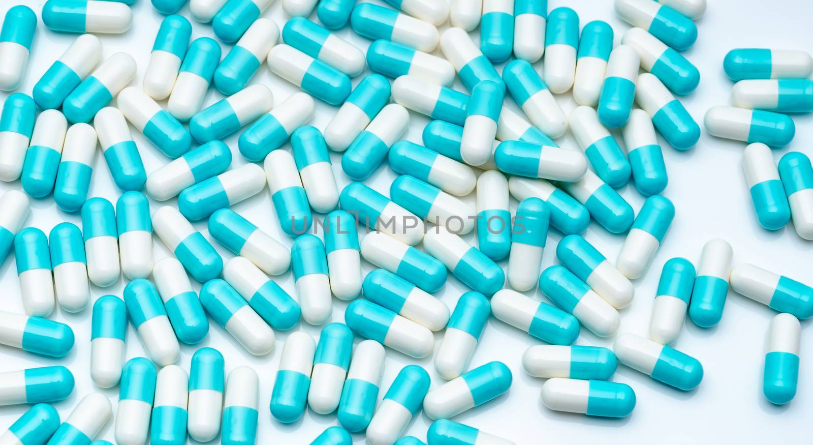 Blue and white capsule pills on white background. Pharmaceutical industry. Blue pastel color capsule pills spread on white table. Pharmaceutics background. Healthcare and medicine. Pharmacy products.
