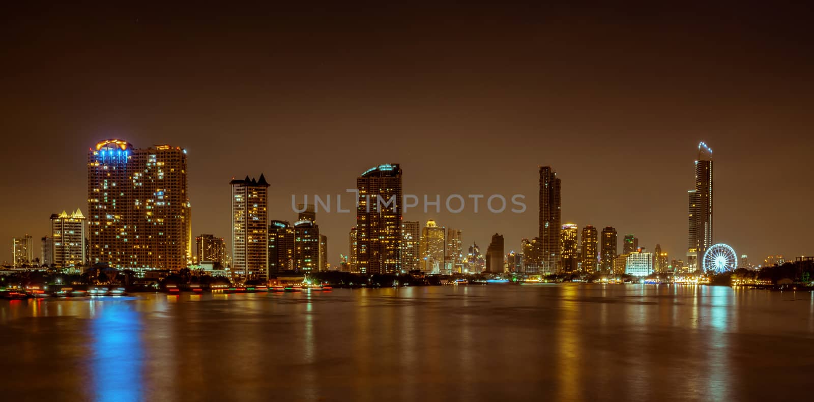 Cityscape of modern building near the river in the night. Modern architecture office building. Skyscraper with evening sky. Night photography of riverfront building. Condominium open light in night. 