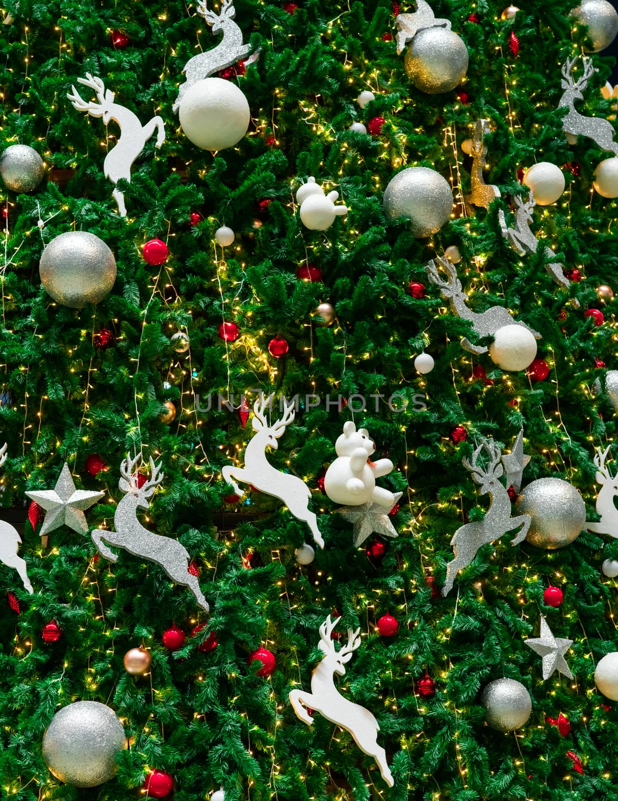 Close up Christmas tree decoration with red, gold, silver, and white balls, silver star and white reindeer. Xmas background. Christmas and Happy New Year background. Colorful ball on Christmas tree.