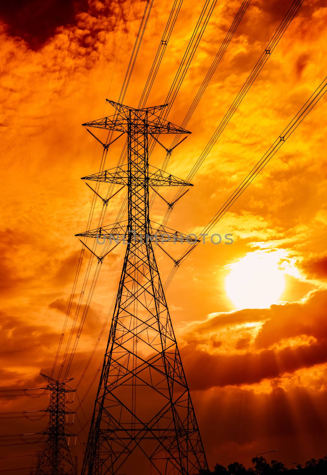 High voltage electric pole and transmission lines. Electricity pylons at sunset. Power and energy. Energy conservation. High voltage grid tower with wire cable at distribution station. Golden sky.