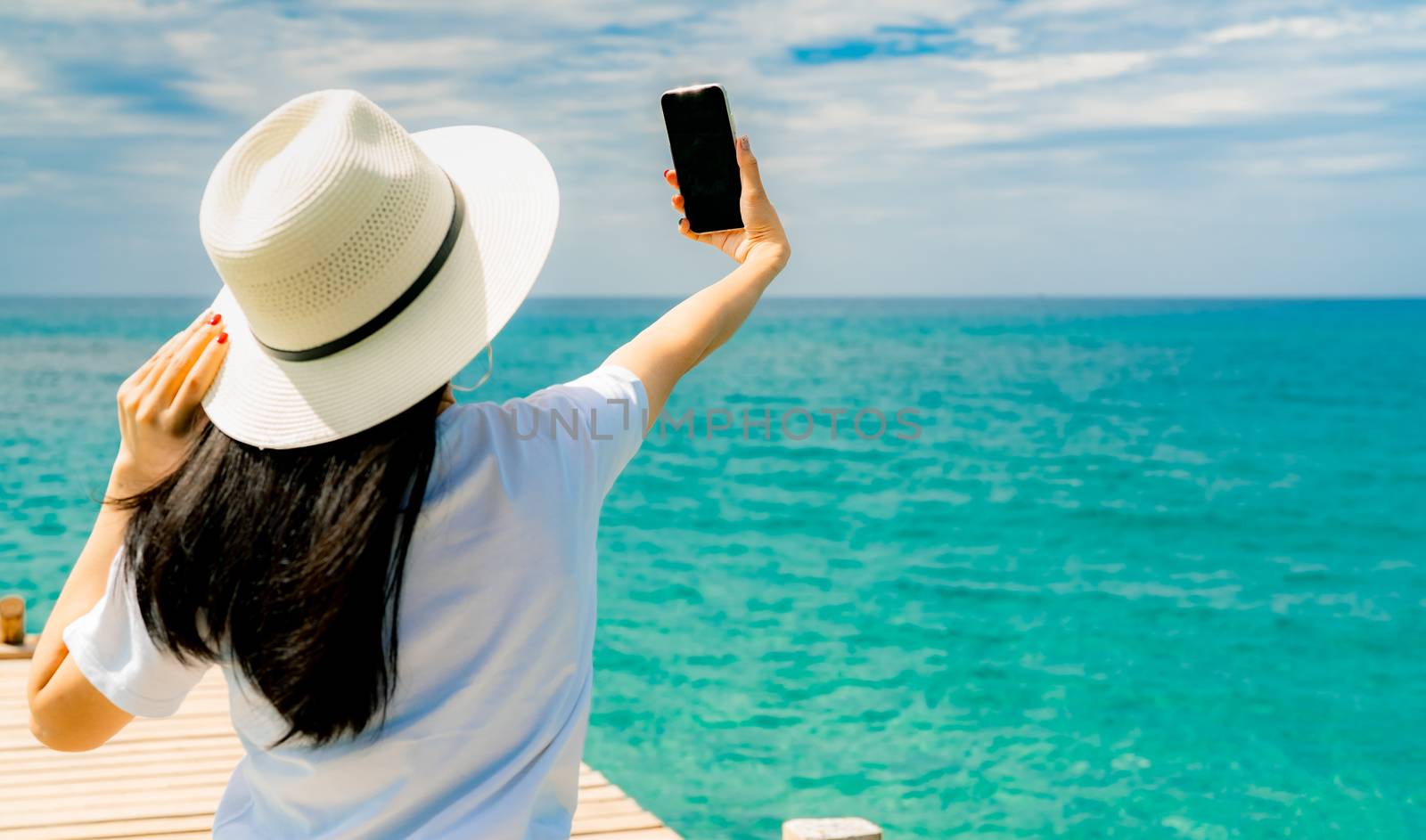 Young Asian woman wear straw hat in casual style use smartphone  by Fahroni