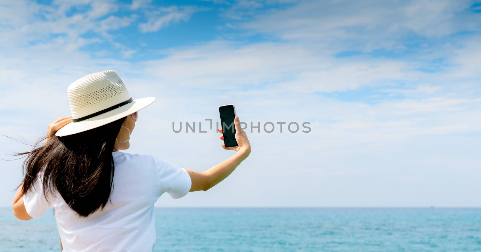 Young Asian woman wear hat in casual style use smartphone taking by Fahroni