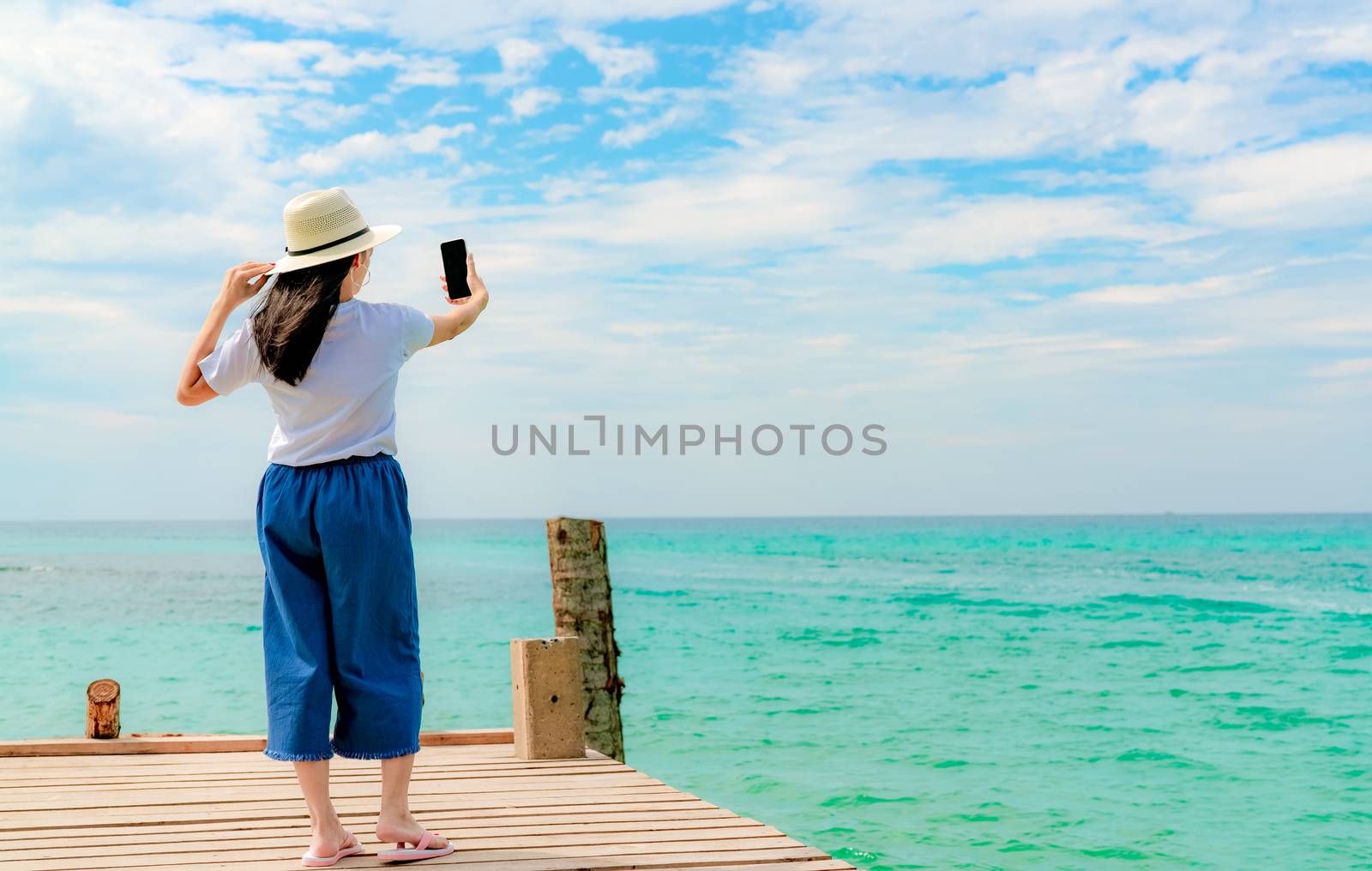 Young Asian woman wear straw hat in casual style use smartphone  by Fahroni