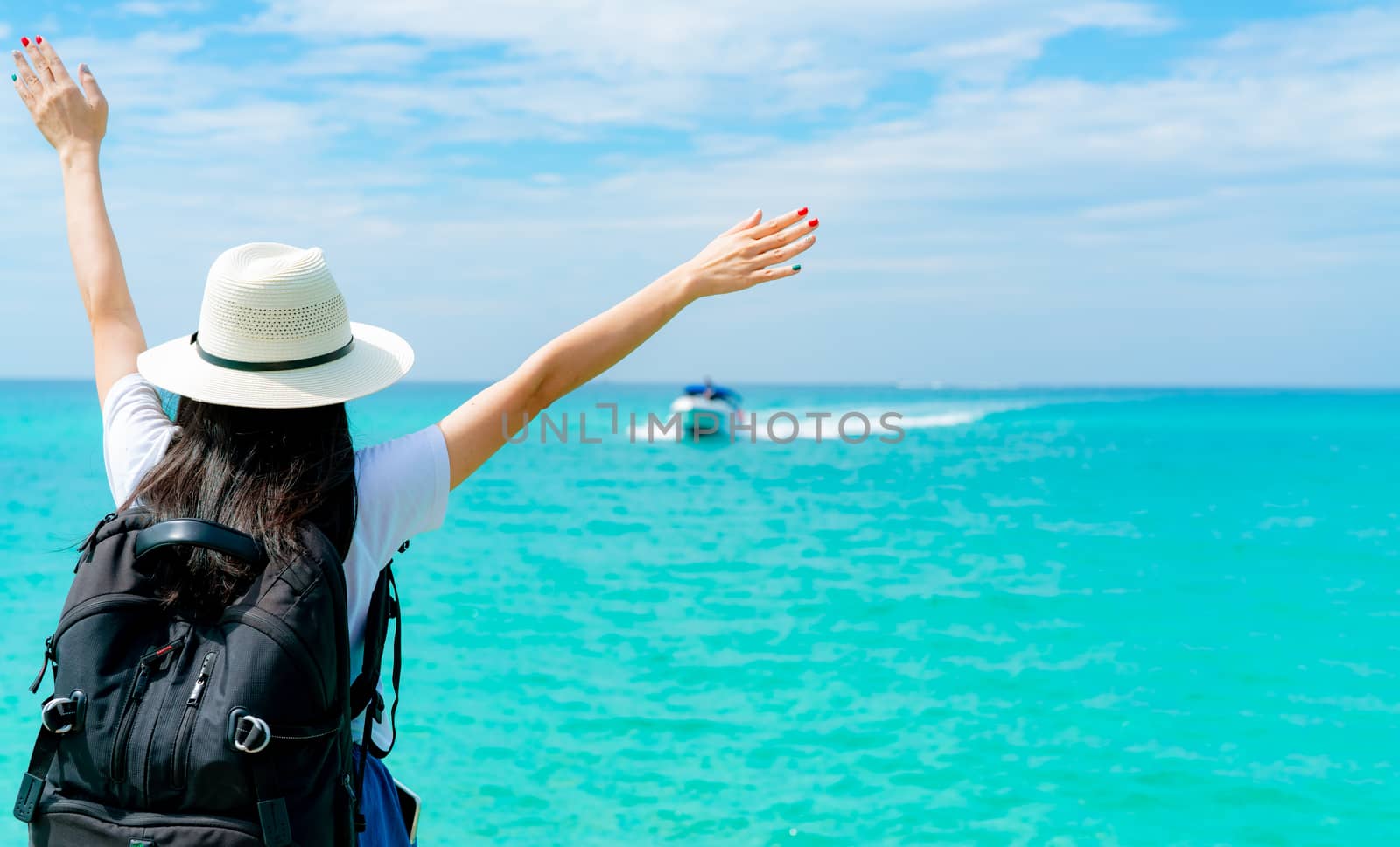 Happy young Asian woman in casual style fashion with straw hat and backpack. Relax and enjoy holiday at tropical paradise beach. Girl stand at the wood pier of resort in summer vacation. Summer vibes.