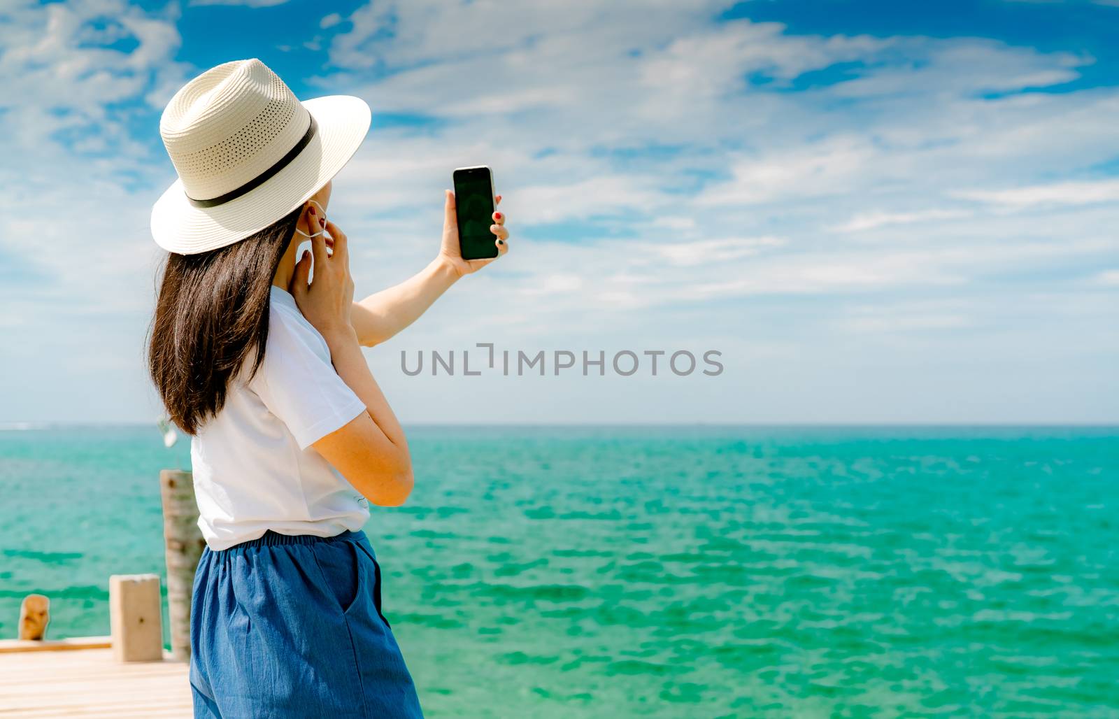 Young Asian woman wear hat in casual style use smartphone taking by Fahroni