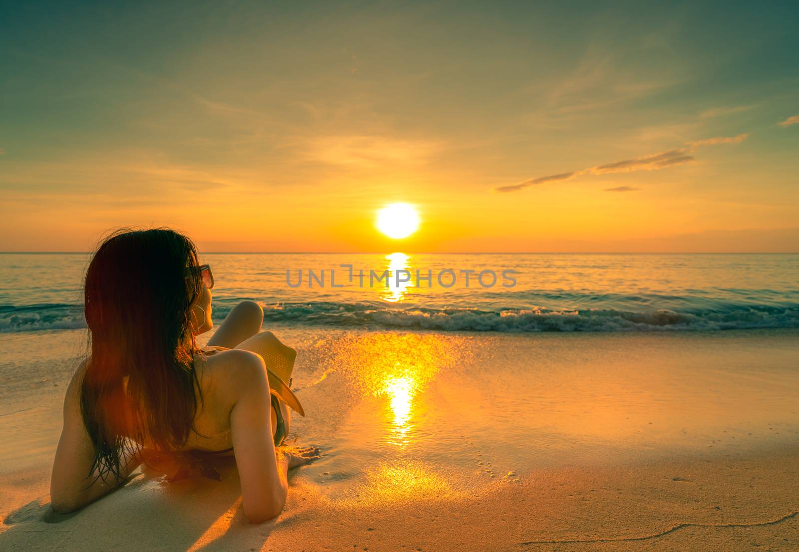 Back view of sexy, enjoy and relax woman wear bikini lying on sand beach with straw hat relax and enjoy holiday at tropical paradise beach at sunset sky. Summer vacation. Holiday travel. Summer vibes.