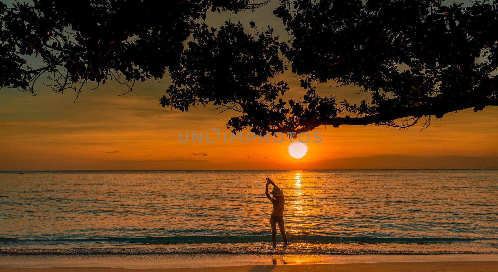 Silhouette back view of sexy woman watching beautiful sunset at tropical paradise beach. Happy girl wear bikini and straw hat relaxing summer vacation. Holiday travel. Summer vibes. Peaceful life.