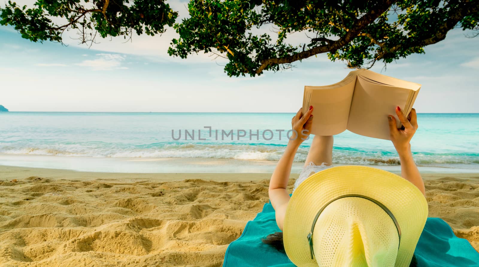 Woman lie down on green towel that put on sand beach under the t by Fahroni