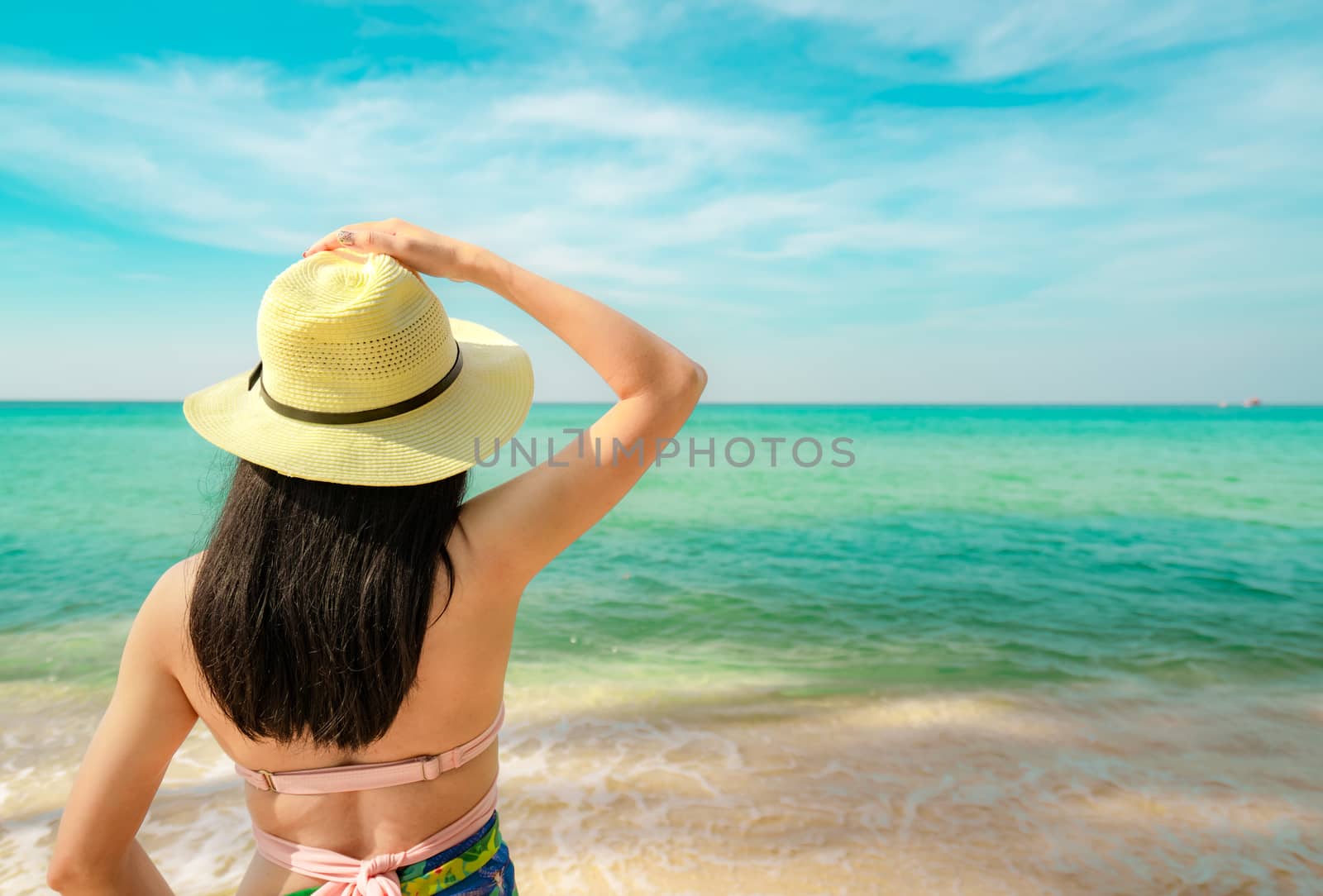 Back view of happy young Asian woman with straw hat relax and en by Fahroni