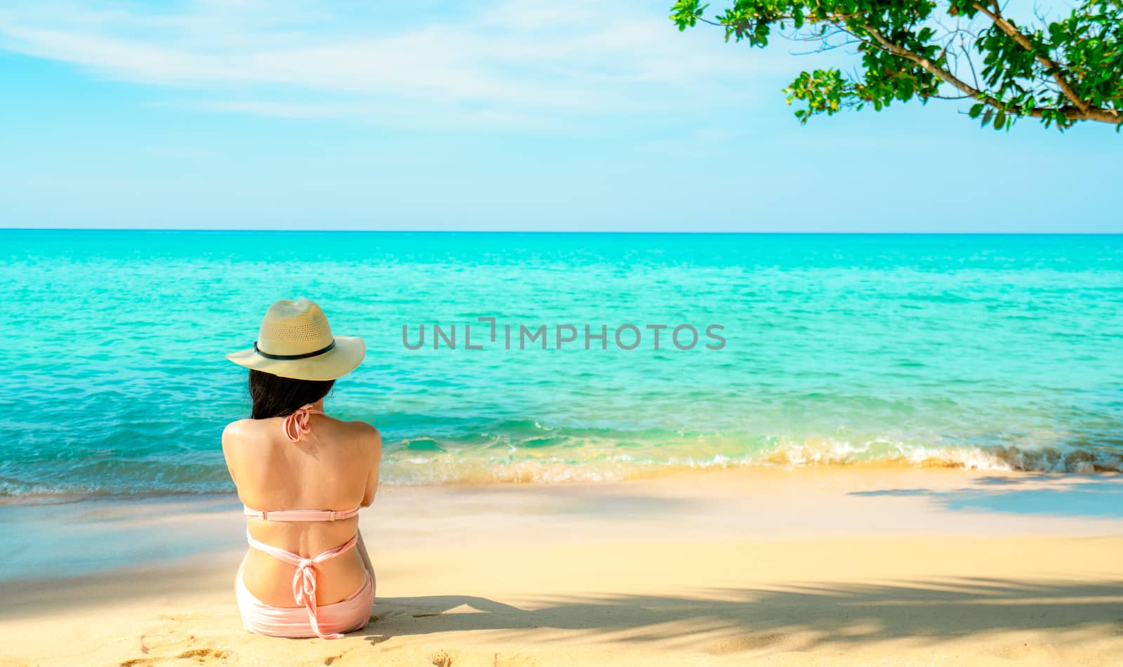 Back view of happy young Asian woman in pink swimsuit and straw  by Fahroni
