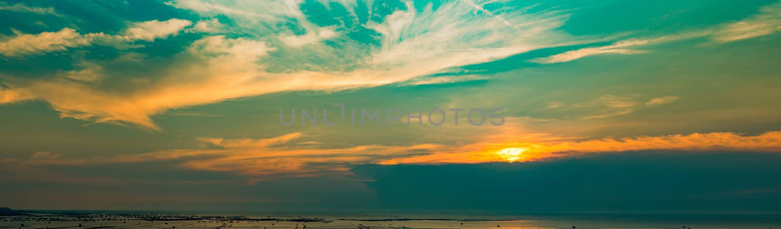 Panorama view of sunset at the beach. Beautiful blue and orange sky and clouds with sunlight. Nature background. Landscape of the beach at tropical sea. Evening sky with peaceful and heaven concept. 