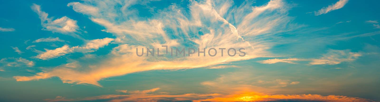 Beautiful blue and golden sky and clouds abstract background. White and golden clouds on sunset sky. Warm weather background. Art picture of sky at sunset. Sunset and fluffy clouds for inspiration.