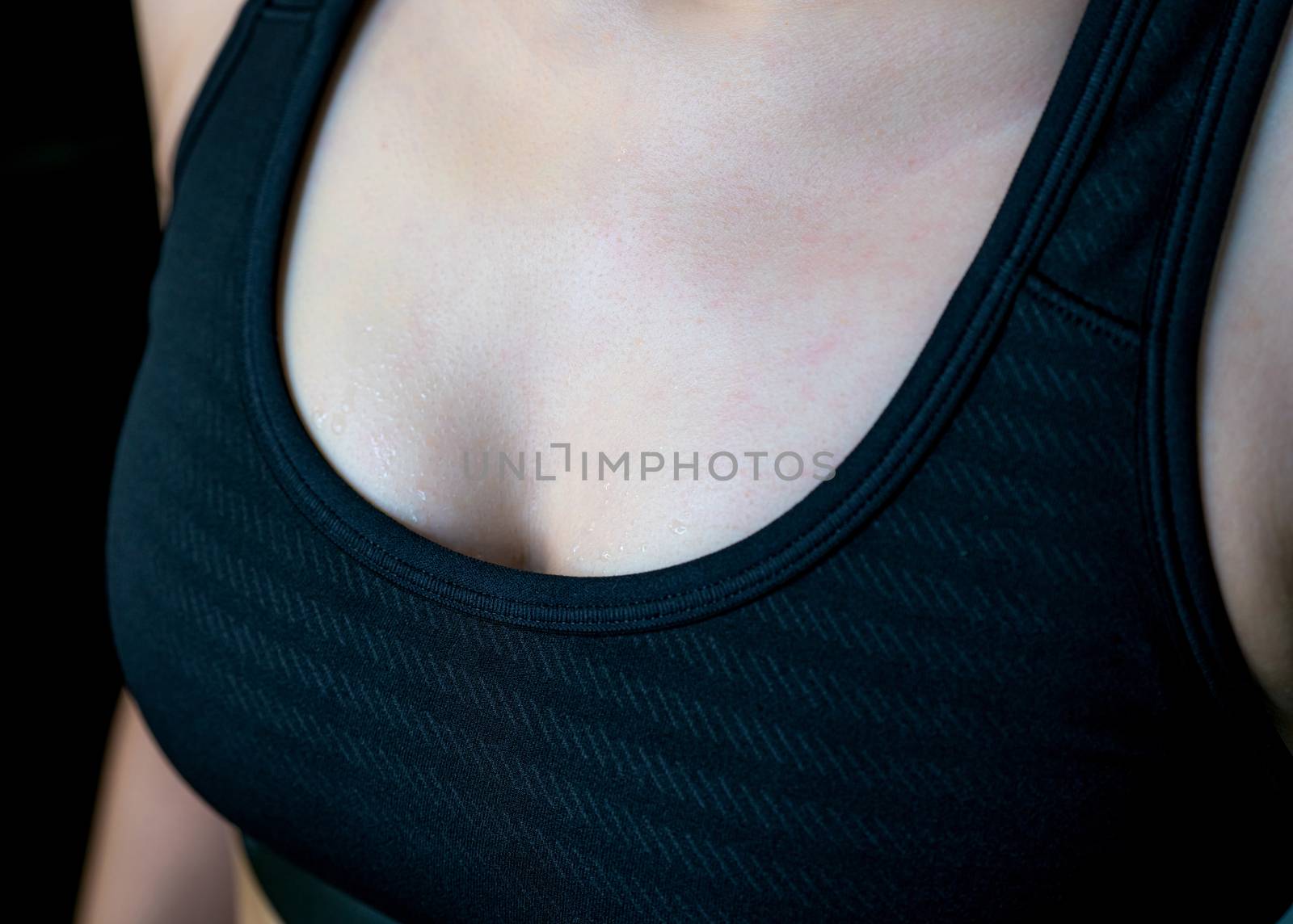 Sweat on woman chest after heavy cardio workout and weight training in gym. Woman chest after workout. Athlete exercise in fitness for fat burning. Healthy lifestyle. Fit woman wear black sports bra.