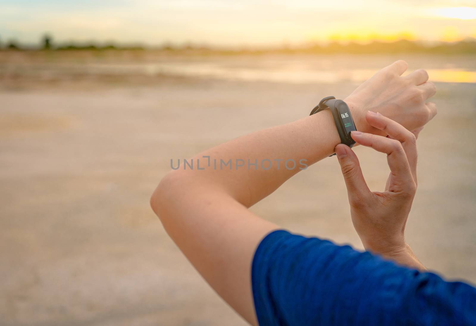 Young Asian woman touching smart band after running in the morni by Fahroni