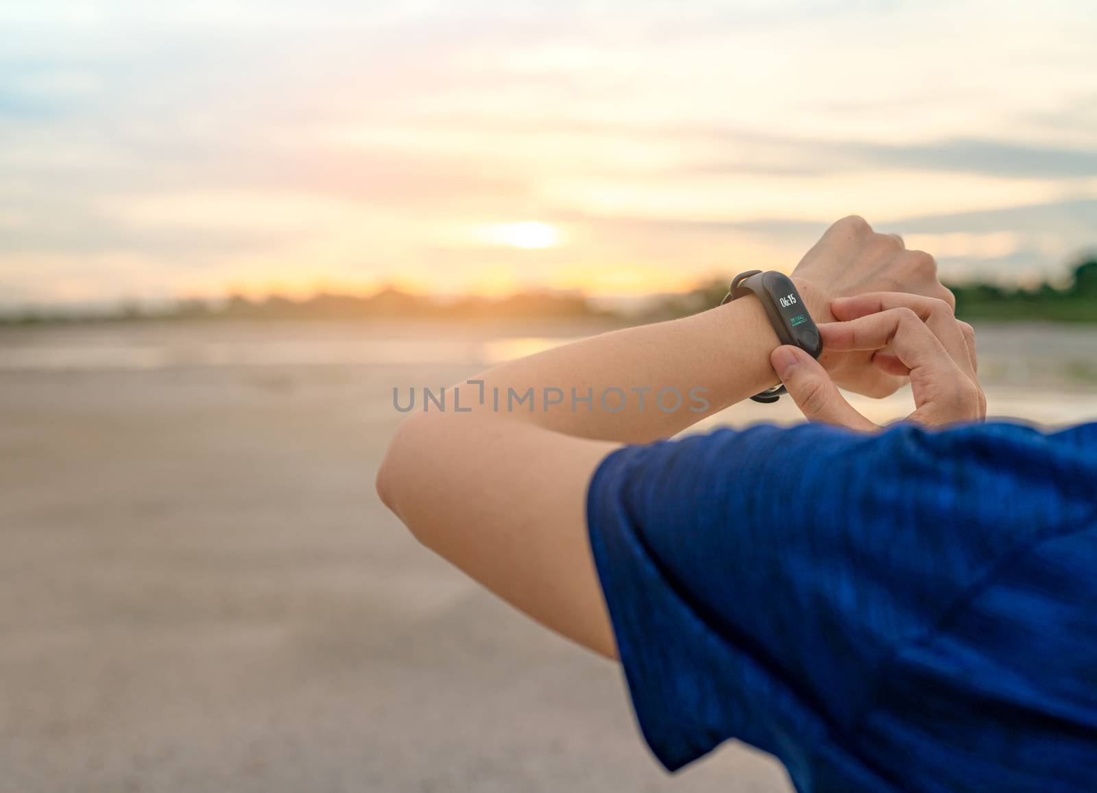 Young Asian woman touching smart band after running in the morning. Wearable computer. Heart rate monitor bracelet. Fitness device. Activity or fitness tracker. Smart watch connected device. Wristband