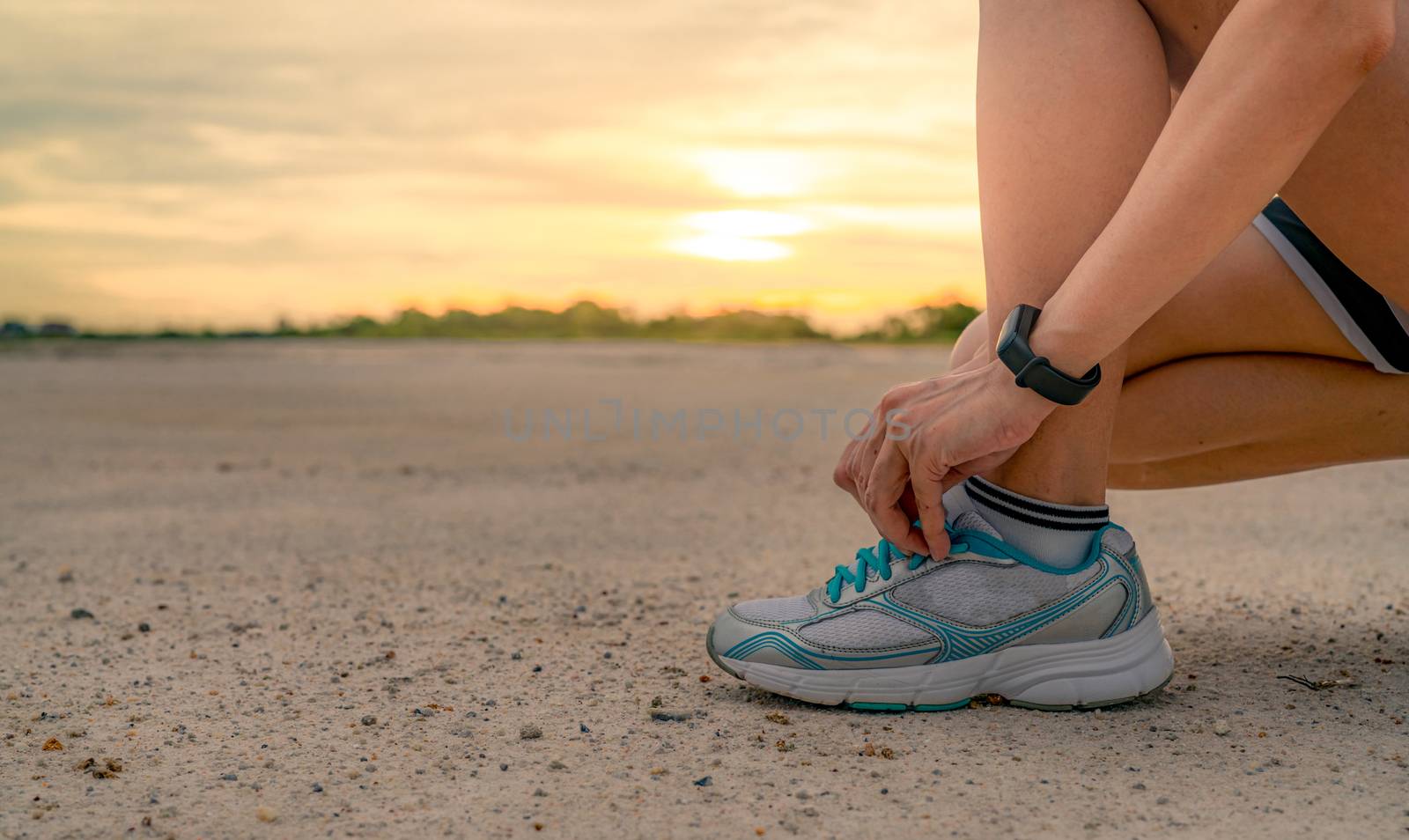 Woman runner tying sport shoes and getting ready for run at the park in the morning. Asian Female cardio exercise for healthy life. Jogging outdoor. Fit girl training for marathon. Summer lifestyle.