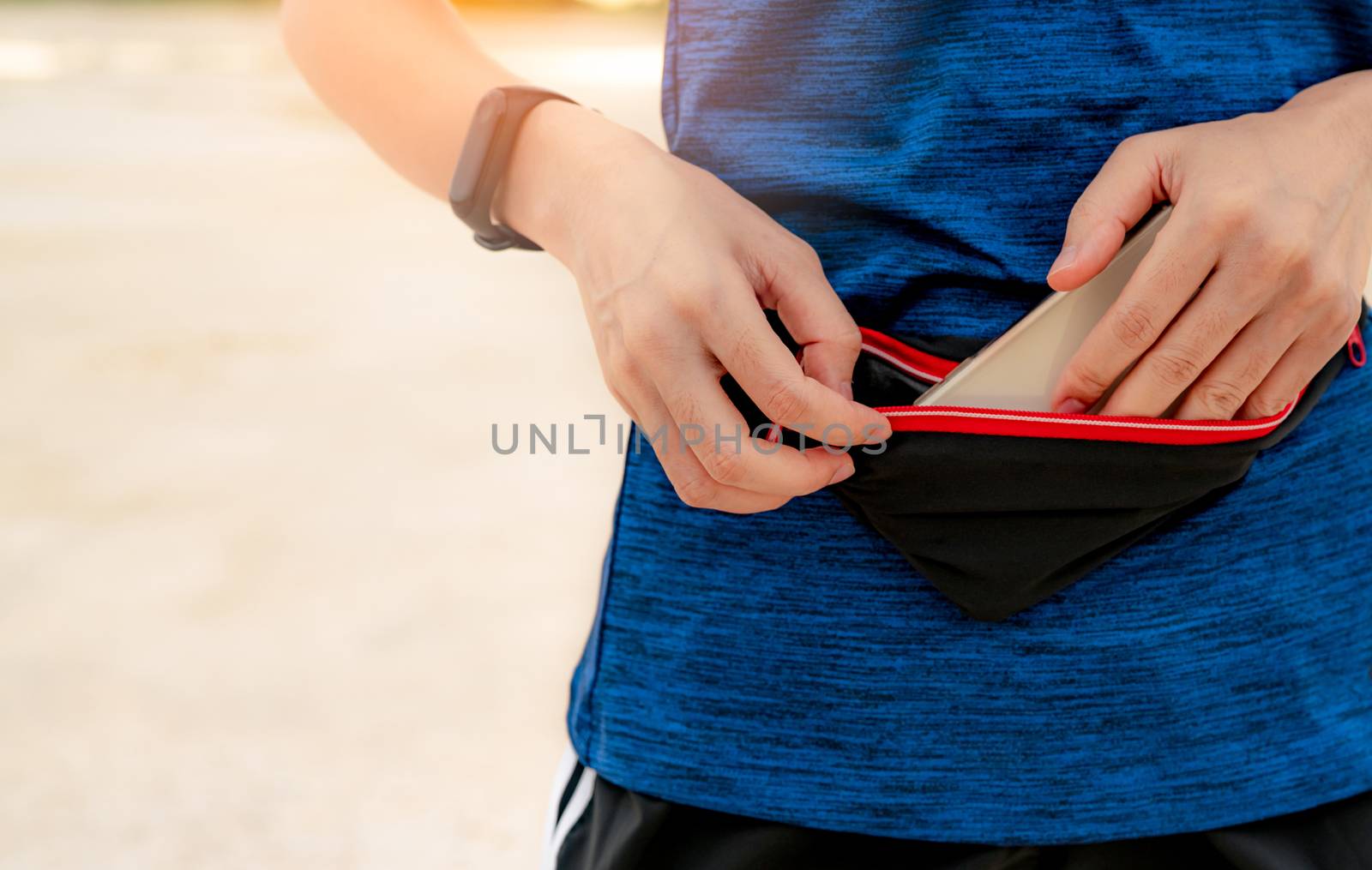 Young Asian woman keep smartphone in waist bag before running ca by Fahroni