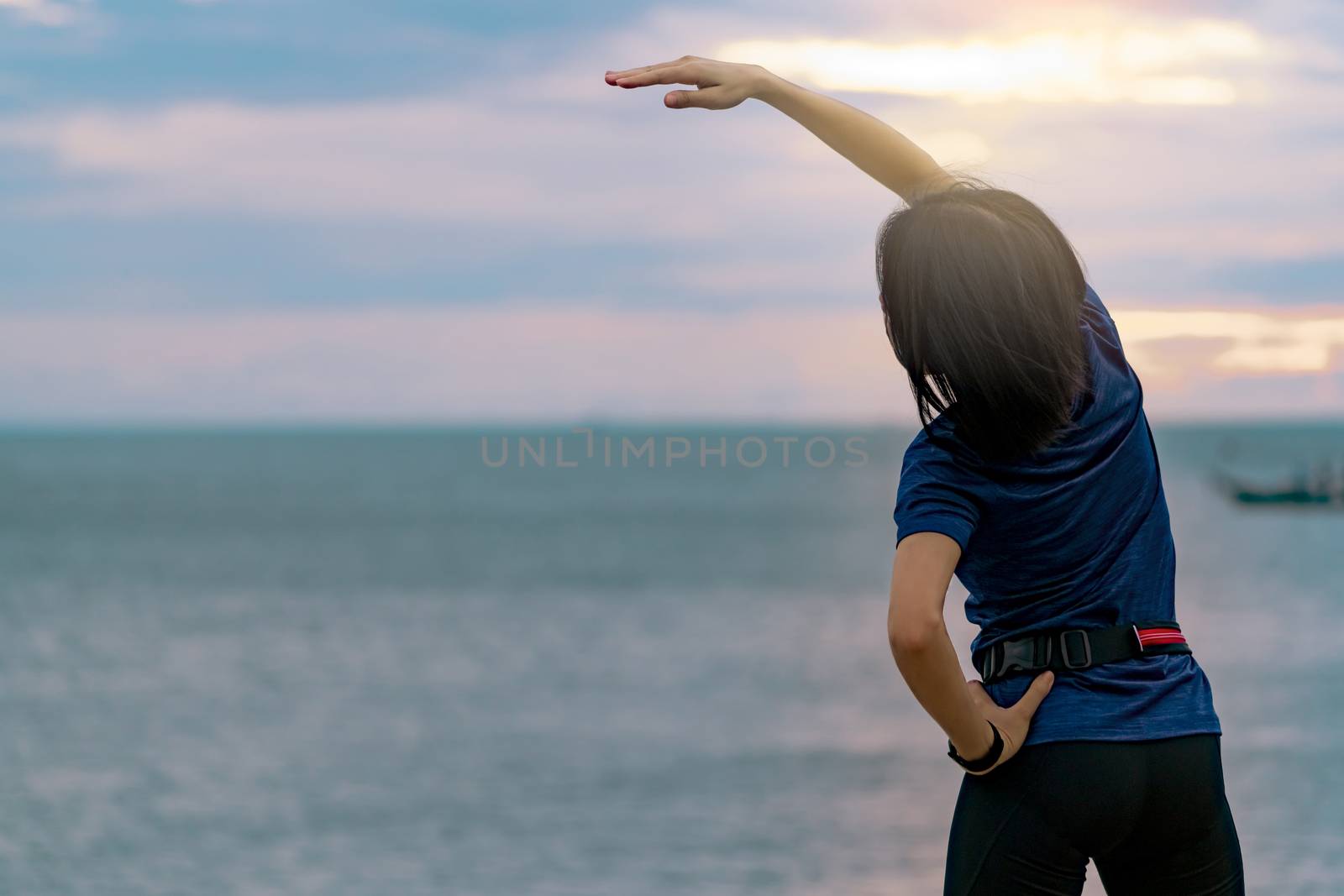 Silhouette woman workout in the morning at stone beach with beautiful sunrise sky. Fit woman runner  stretching body before running. Cardio exercise for healthy lifestyle. Active girl workout alone.