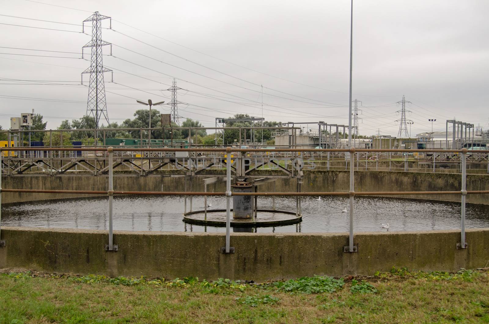 View of a primary settlement tank at a sewage treatment works on an overcast afternoon in Autumn.  Sewage is left in the circular tank and solids fall to the bottom to be scraped up and pumped away.  