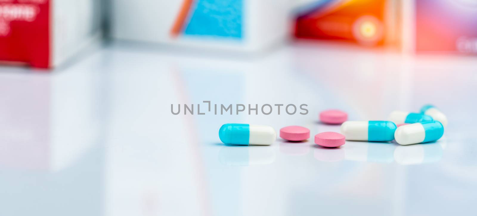 Round pink tablets pill and white-blue capsule pills on blurred  by Fahroni