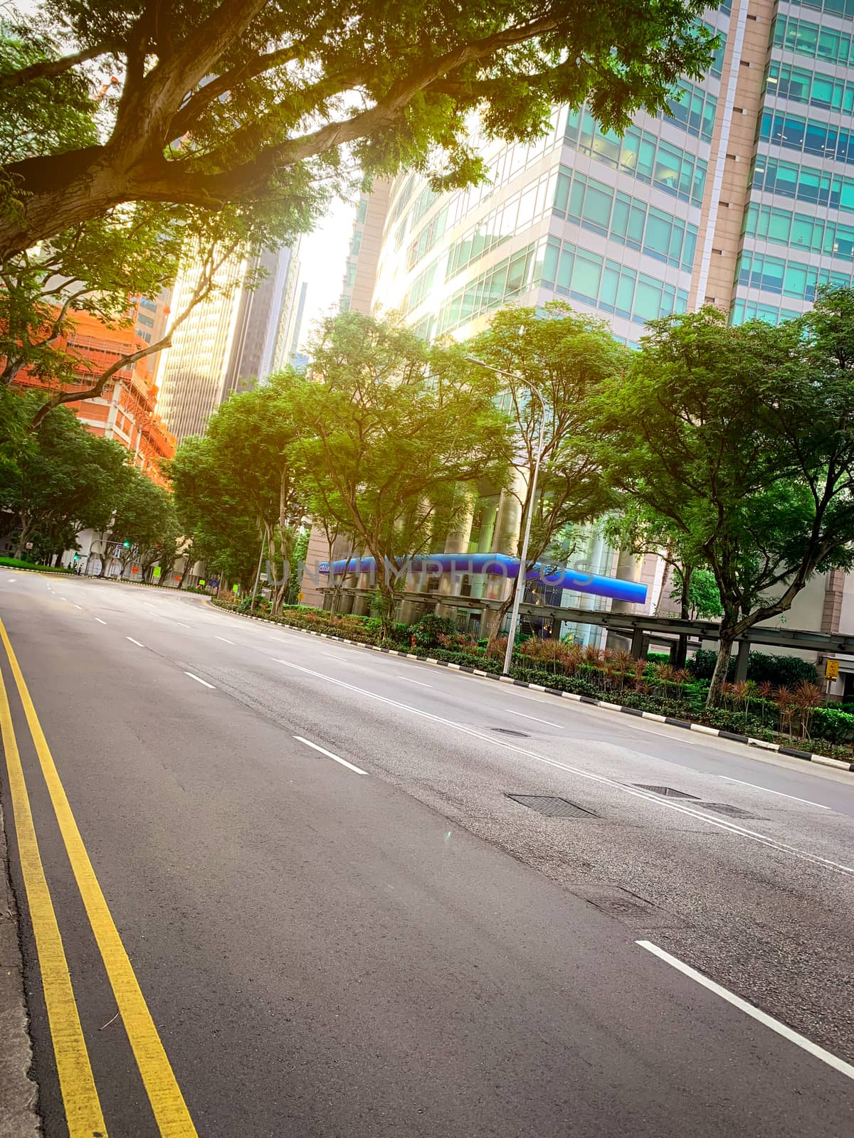 Empty asphalt road in city. Green city with skyscraper modern office building. Business and financial center glass building. Cityscape. Green tree beside the road for reduce dust and air pollution.