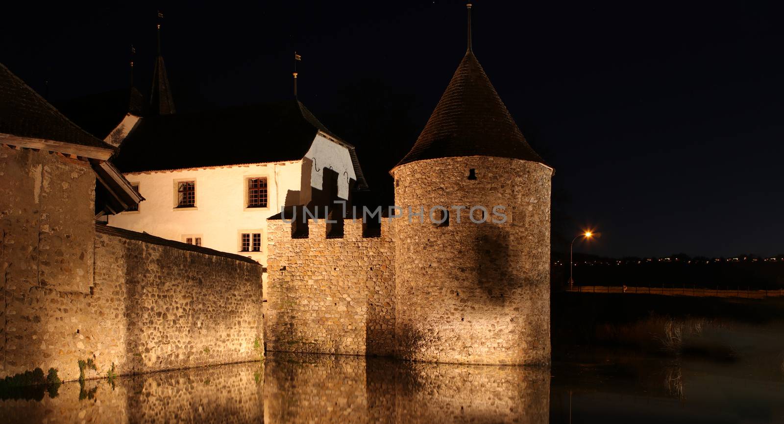 Schloss Hallwil, castle in Switzerland at night with reflection in river.