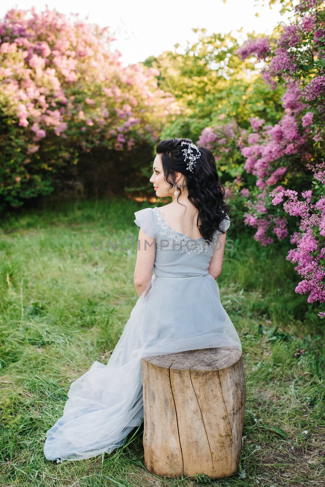 portrait of a brunette girl in a lilac spring garden before the wedding ceremony