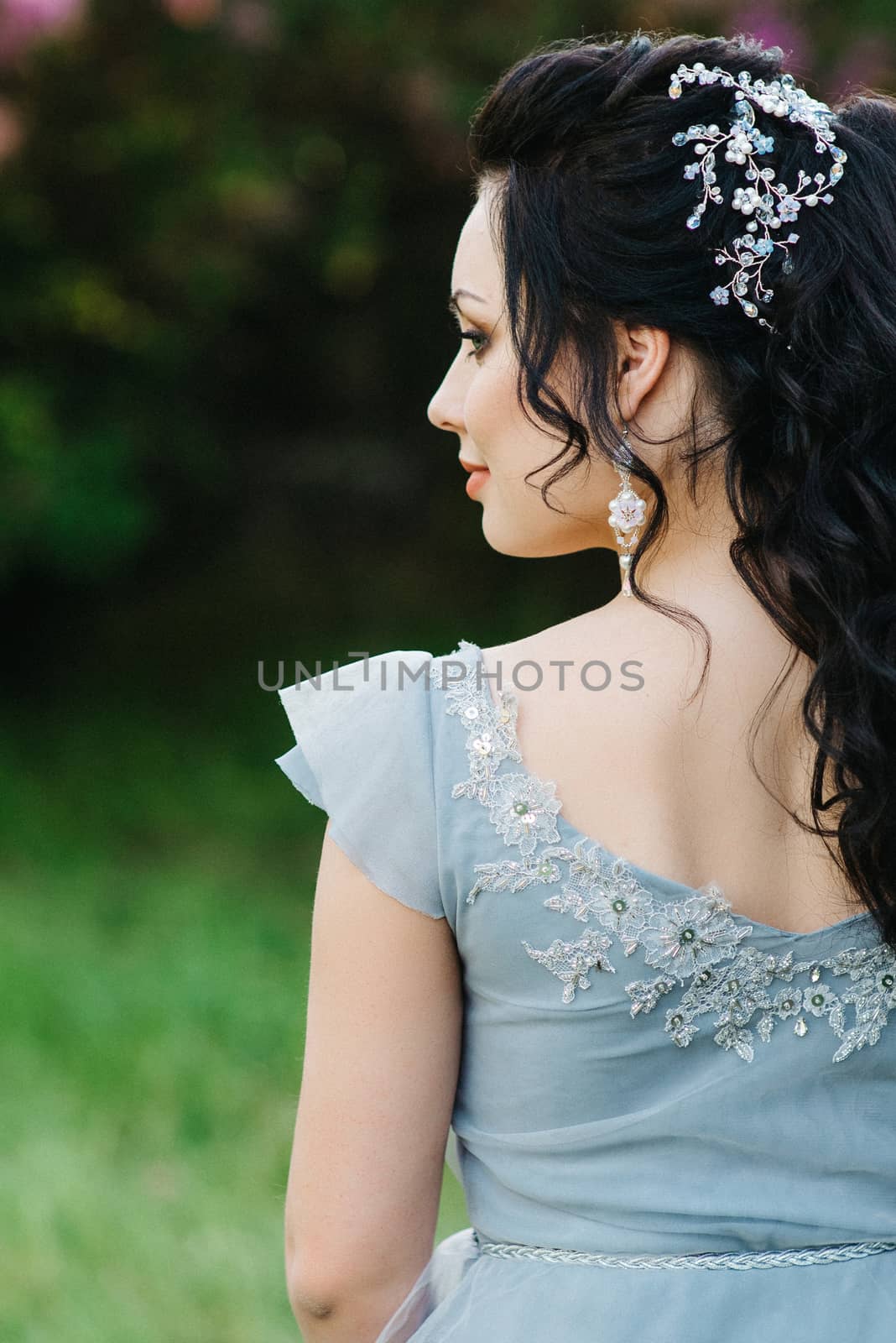 portrait of a brunette girl in a lilac spring garden before the wedding ceremony