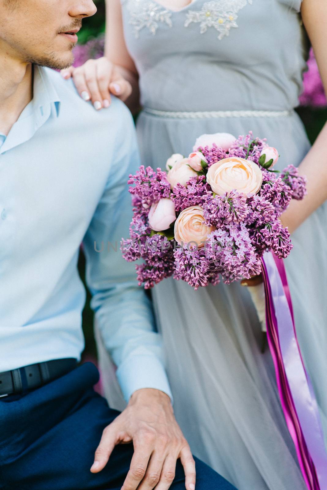 a guy and a girl walk in the spring garden of lilacs before the wedding ceremony