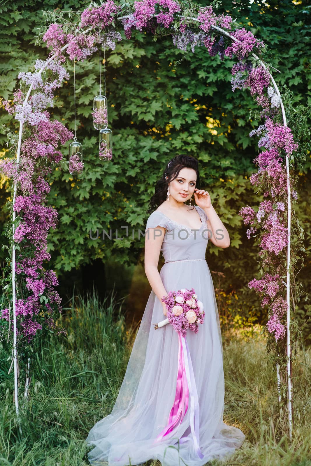 portrait of a brunette girl in a spring garden of lilacs before the wedding ceremony on the arch