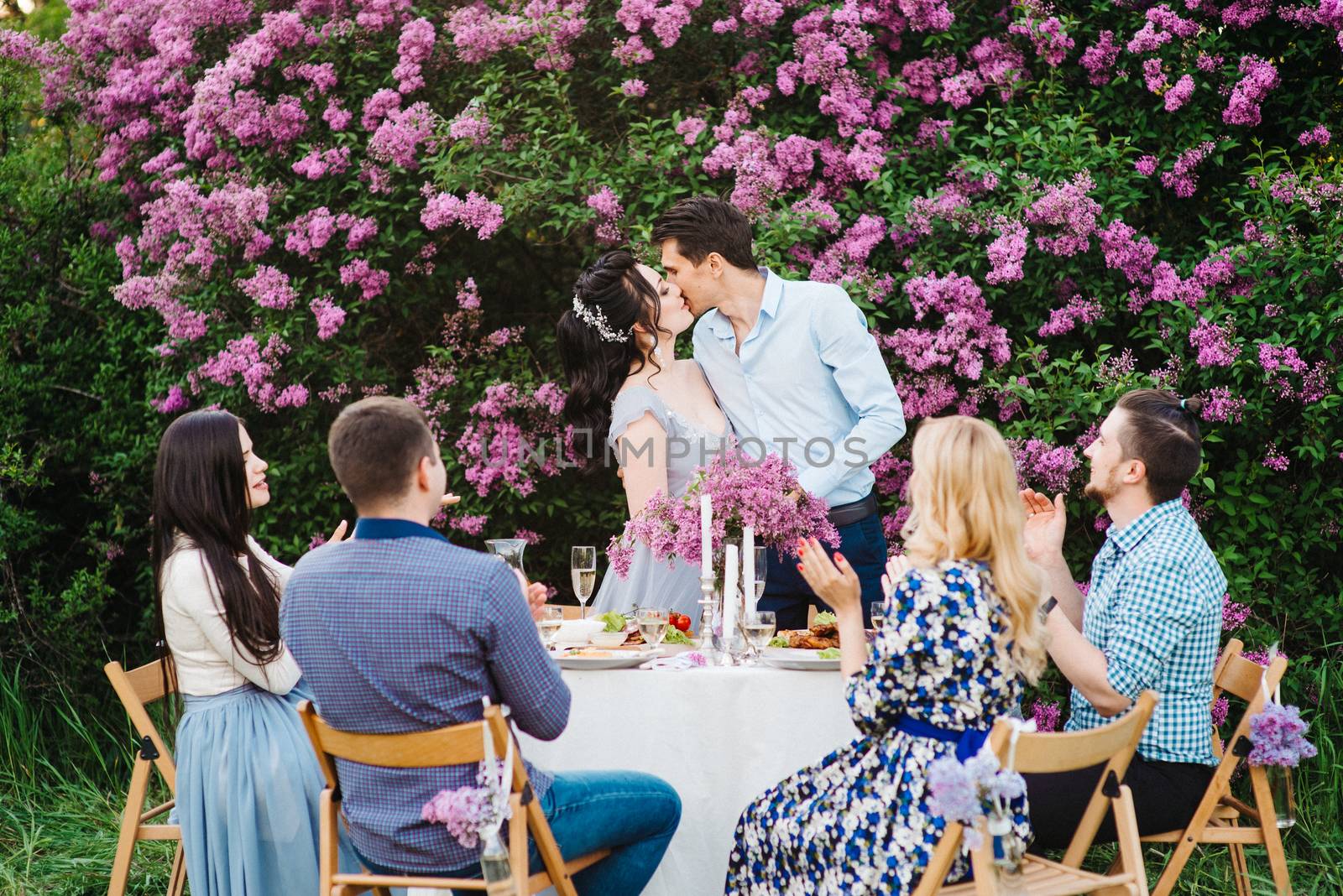 bride and groom at a wedding table with friends in a spring garden