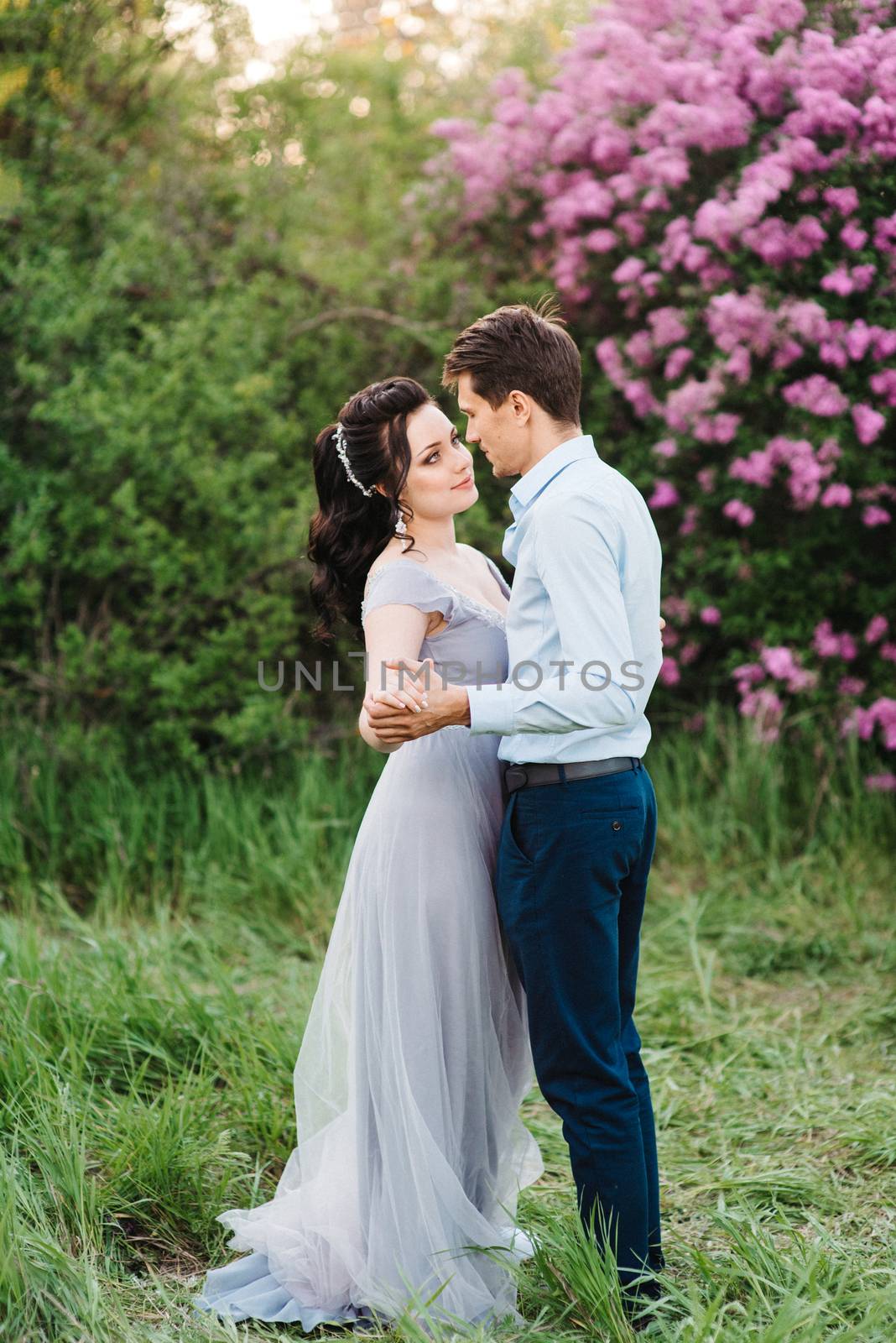 a guy and a girl walk in the spring garden of lilacs by Andreua