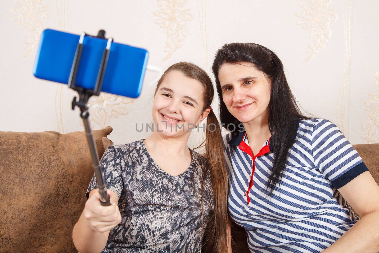 mom and daughter take selfie with smartphone while sitting on the sofa at home. coronavirus quarantine.