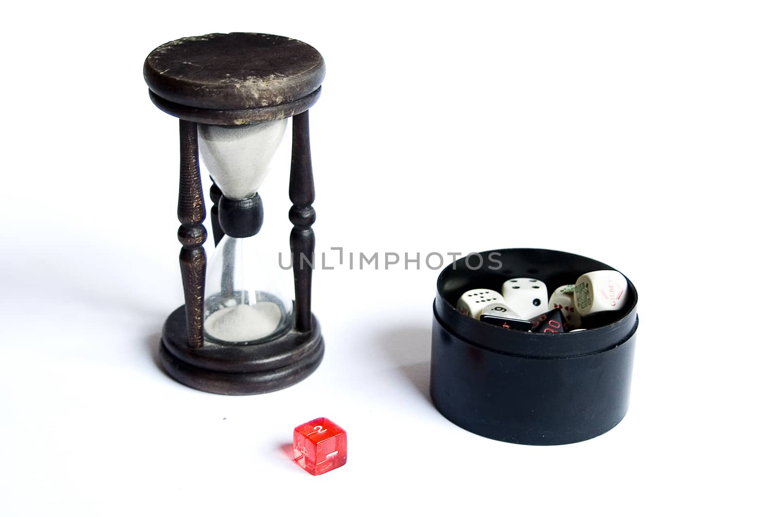 old wooden hourglass with a strap on a white background and dice in a black container