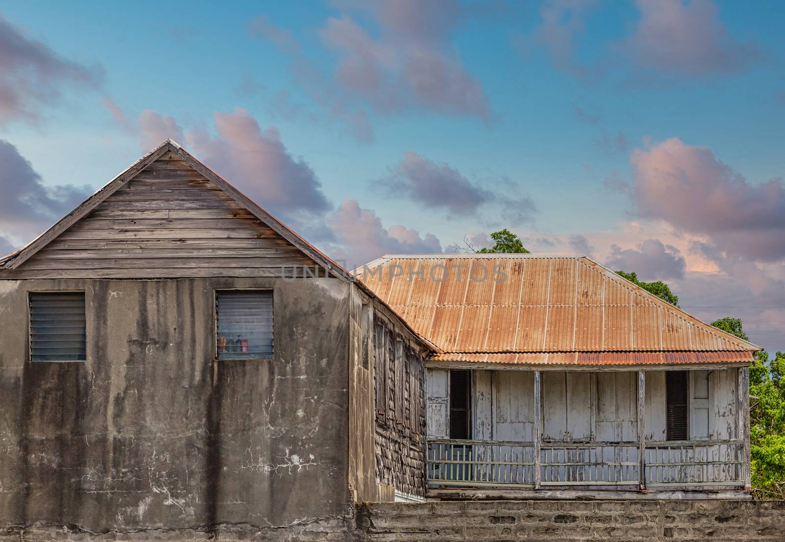 An old abandoned cement building with a rusty tin roof