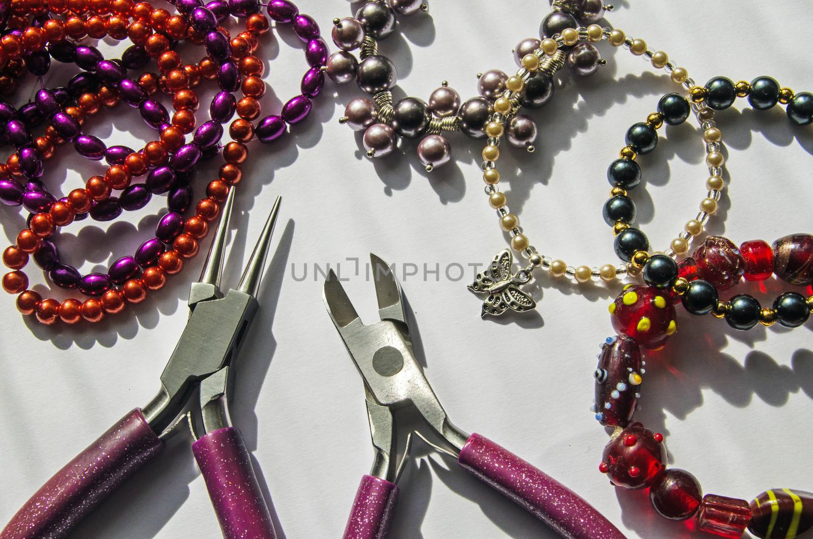 A selection of beads and tools used to make bracelets with the finished products shown too.