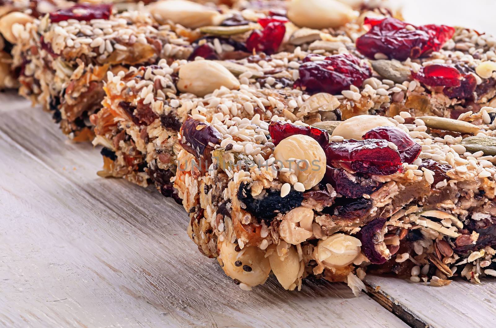 Granola bar. Healthy sweet dessert snack. Cereal granola bar with nuts, fruit and berries on a white wooden table. Closeup.